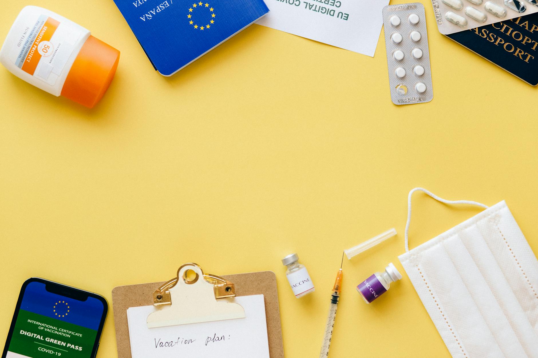 Flat lay of travel essentials including passport, mask, and vaccination pass.