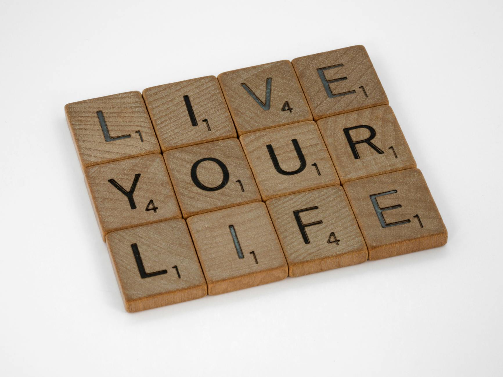 Scrabble tiles form the phrase 'Live Your Life' on a white background.