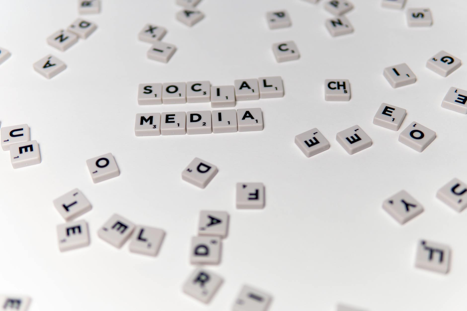 White Scrabble tiles forming the phrase 'social media' on a scattered background.