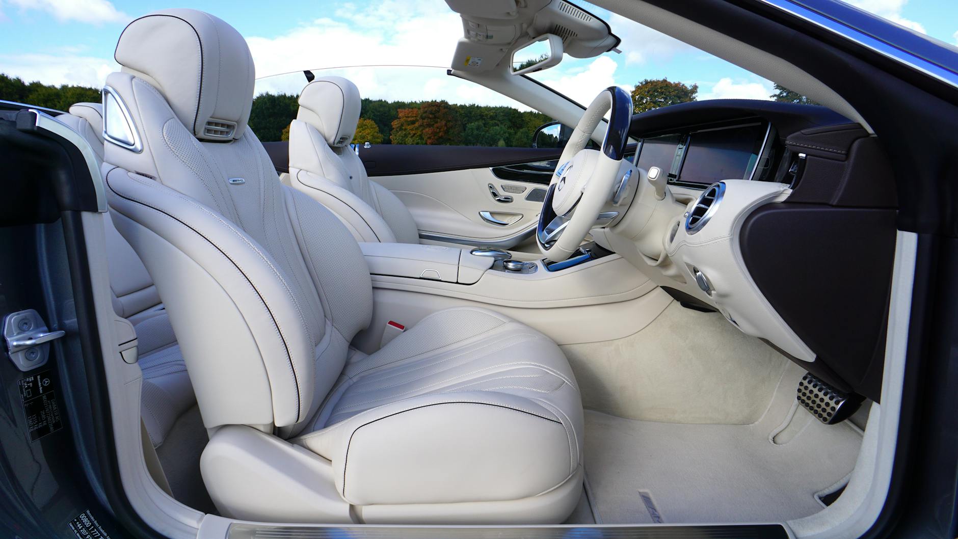Elegant Mercedes convertible with cream leather seats and advanced dashboard in open top view.