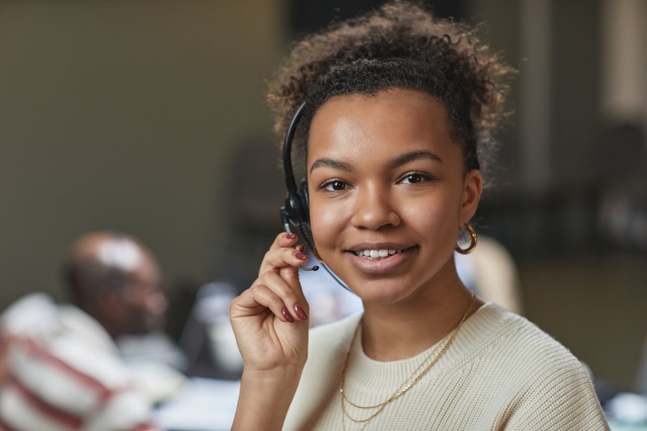 home-services-01 Friendly woman in a call center environment, wearing a headset and smiling.