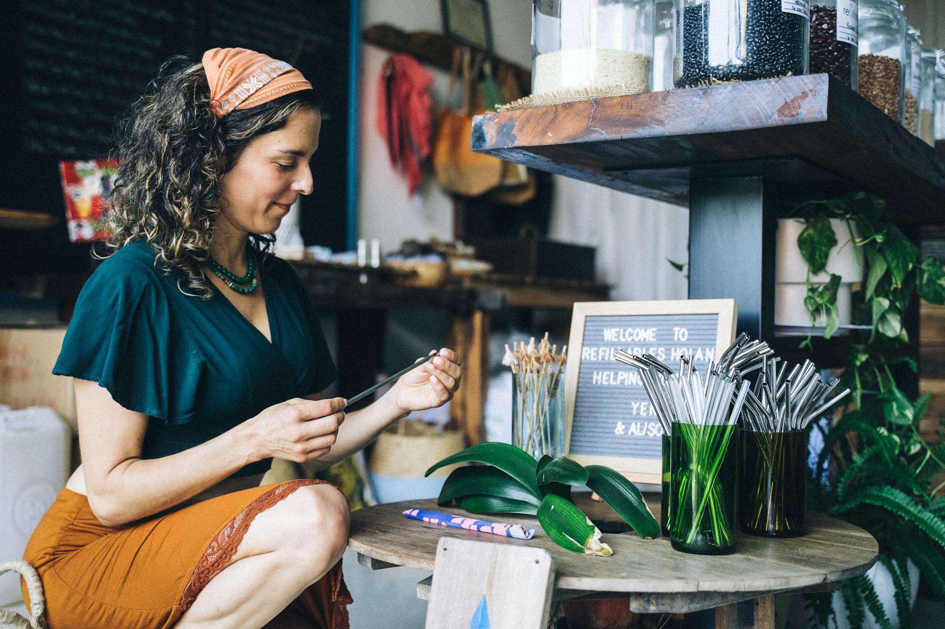Woman in store with reusable straws and eco-friendly products promoting sustainability.