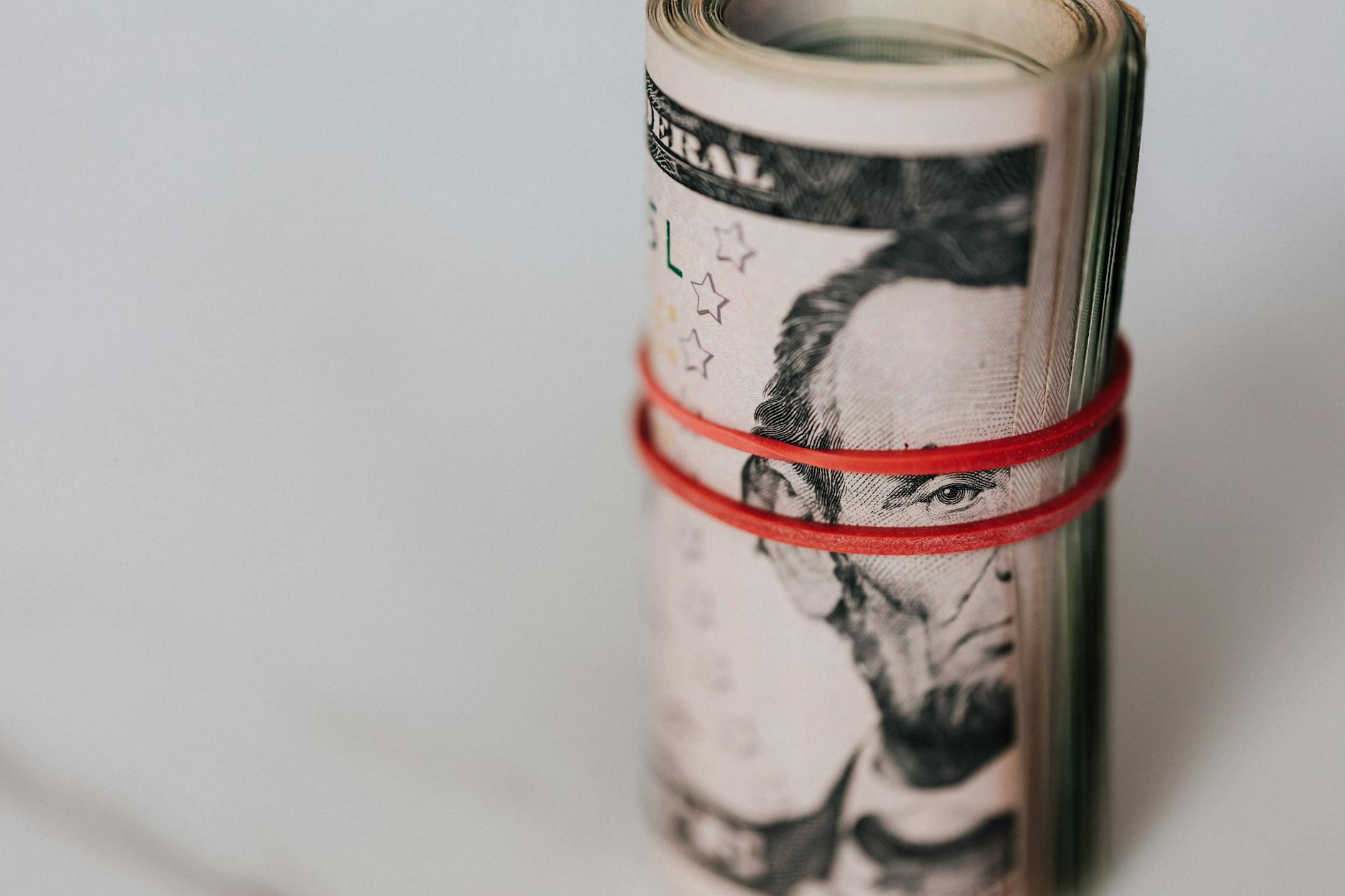 Close-up of a roll of US dollars wrapped with a red rubber band focusing on financial abundance.