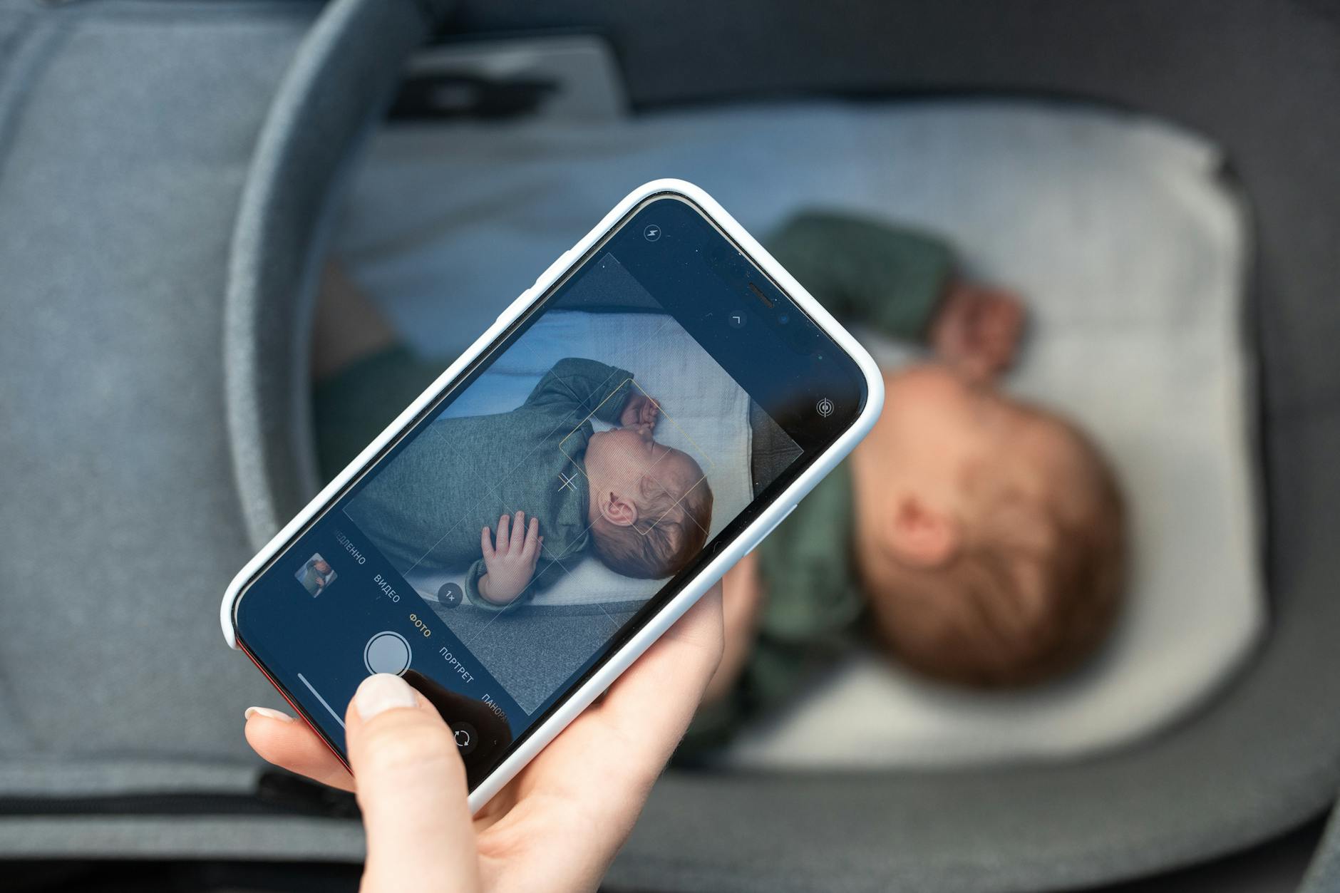 A smartphone capturing a peaceful newborn baby sleeping in a crib, highlighting modern parenthood.